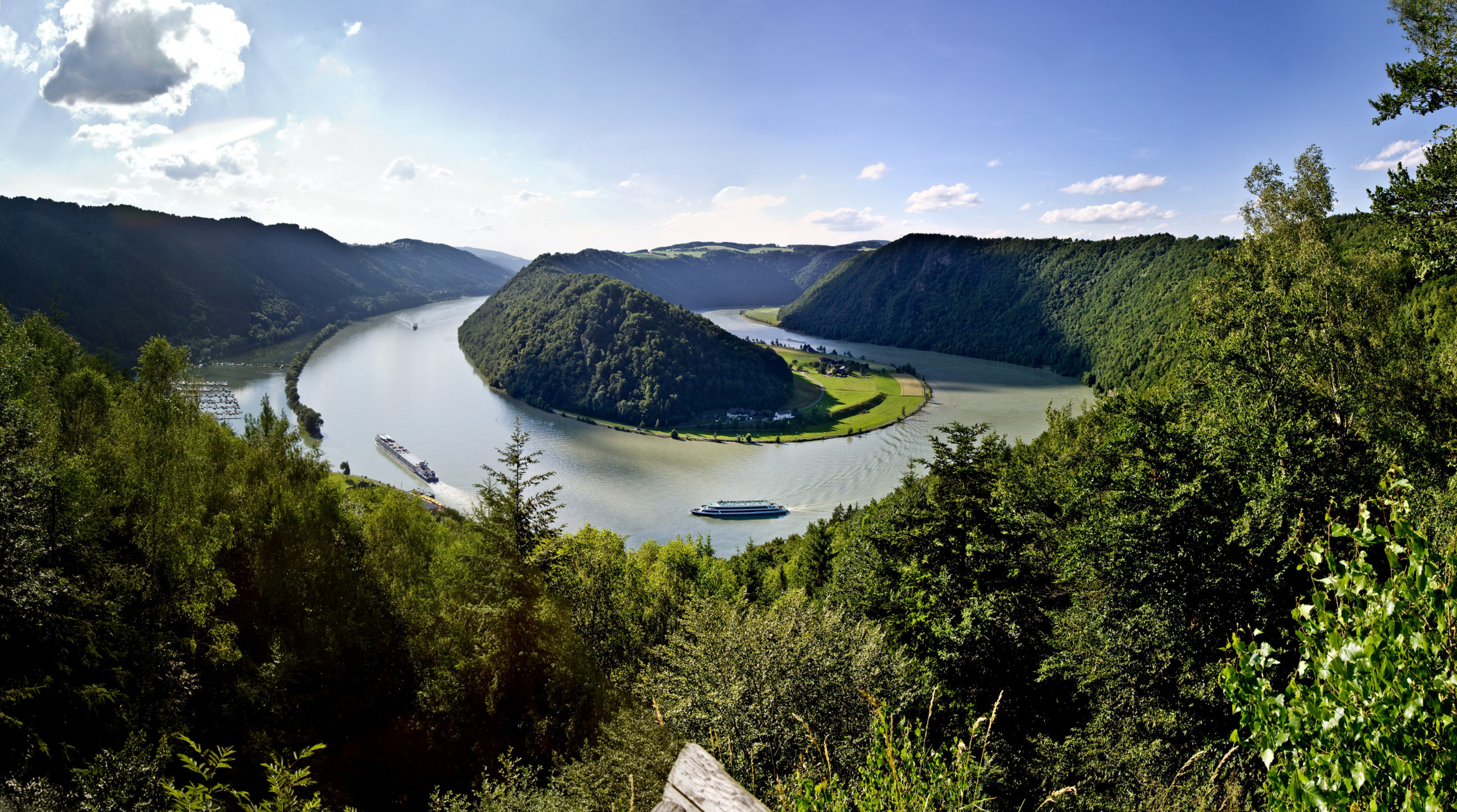 Cycling along the scenic Danube River with a boat in the background, part of the Danube Boat & Bike tour featuring picturesque landscapes, European countryside, and cultural landmarks.